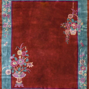 Burgundy rug with a turquoise floral border and detailed pink and lavender floral vase patterns.