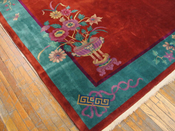 High-pile rug featuring a red field, colorful floral designs, and a wide turquoise border on wood flooring.