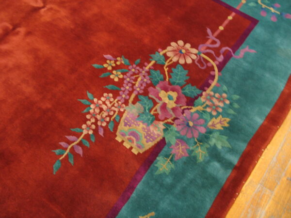 Detailed view of a high-pile rug featuring a floral basket motif, rust field, and wide teal border.