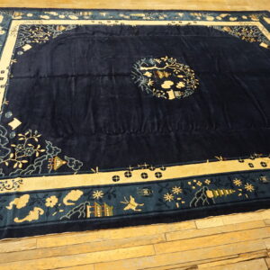 Dark blue patterned rug with light gold and teal borders lies on aged wooden floorboards.