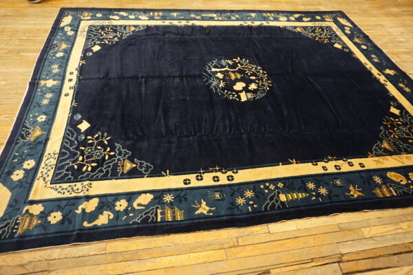 Dark blue patterned rug with light gold and teal borders lies on aged wooden floorboards.