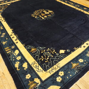 Navy rug featuring yellow and teal borders with stylized pagodas and flowers over light wooden planks.