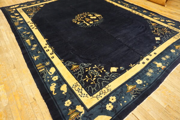 Navy rug featuring yellow and teal borders with stylized pagodas and flowers over light wooden planks.
