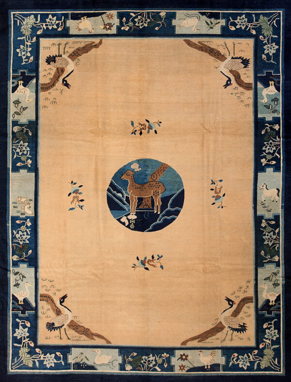 Tan rug with a navy blue border featuring detailed corner cranes and animal motifs in light blue cartouches.