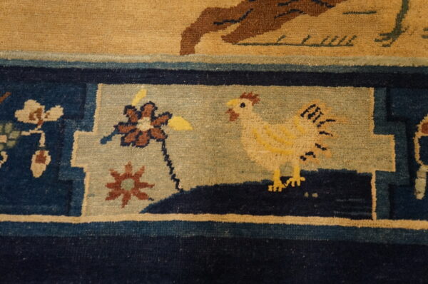Navy blue and light blue rug border featuring a yellow chicken and floral patterns on a beige background.
