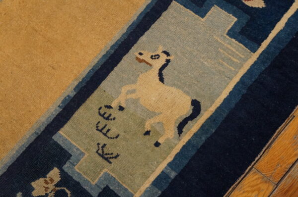 Tan rug featuring a cream horse and symbols in a blue and sage decorative border on wood floor.