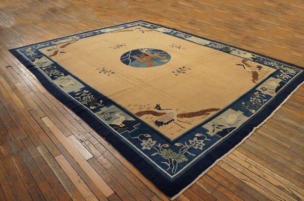 Low pile beige rug with a circular medallion and wide blue pictorial borders on wood planks.