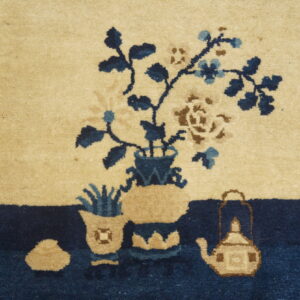 Detail of a high-pile rug showing blue and brown flowers in vases above a dark navy border.