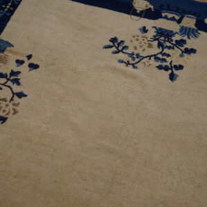 Beige rug featuring a dark blue border and stylized blue floral patterns on a light brown wooden floor.