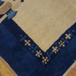 A high-pile rug corner features a navy blue border, beige field, and stylized floral motifs on wood planks.
