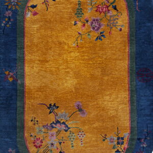 Oval rug with a yellow field, blue border, and colorful flowering vine decorations.