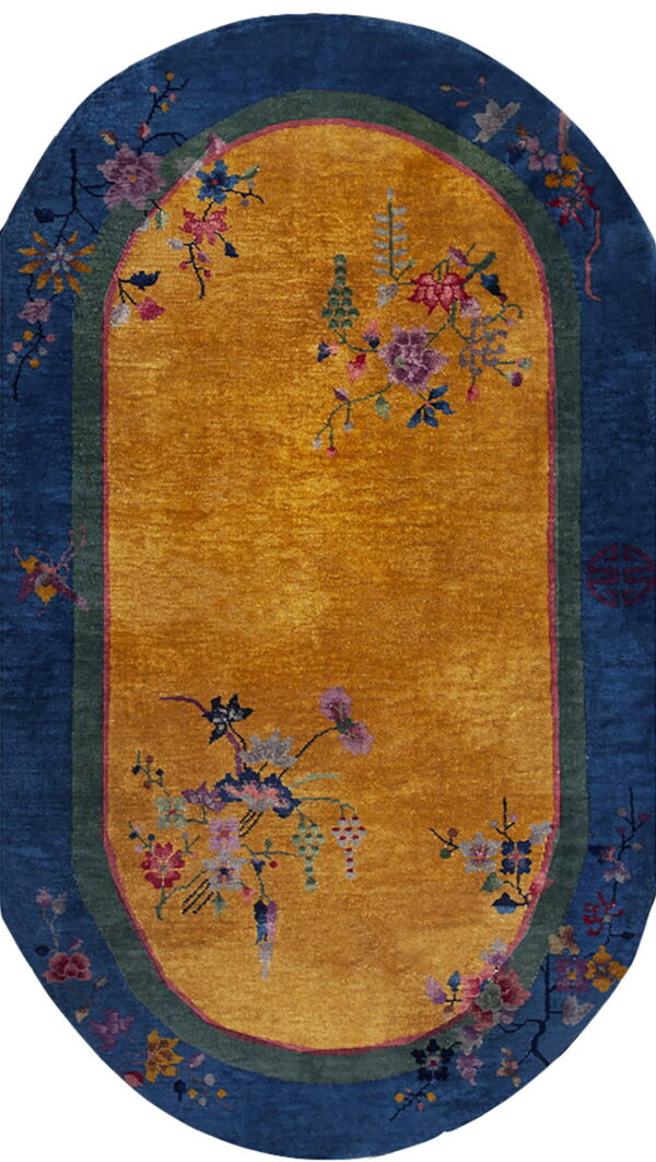 Oval rug with a yellow field, blue border, and colorful flowering vine decorations.