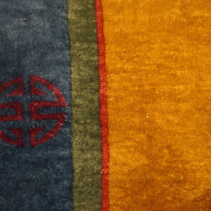 High-pile rug showing gold and blue fields, vertical stripes, and a central red circular geometric motif.