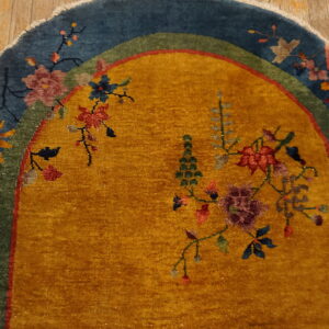 Mustard yellow rug with blue and green borders displays colorful floral motifs on distressed wood flooring.