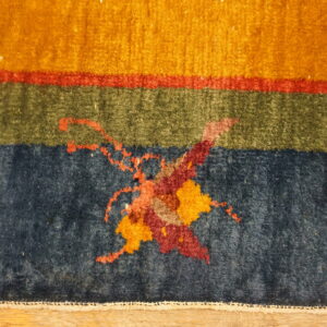 Abstract rug detail showing bands of gold, red, green, and navy with a stylized central pattern.