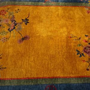 Oval rug with a gold center, colorful floral motifs, and borders in dark blue and olive green.
