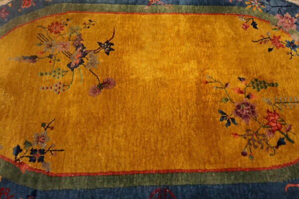 Oval rug with a gold center, colorful floral motifs, and borders in dark blue and olive green.