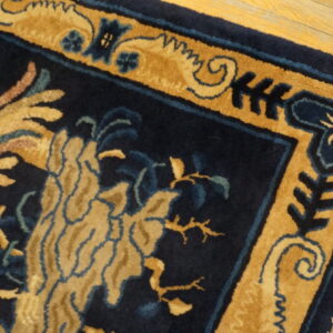 High-pile navy rug with gold and teal floral motifs and bordered patterns on wood flooring.