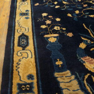 Plush navy rug with gold, blue, and pink stylized floral patterns borders light wood flooring.