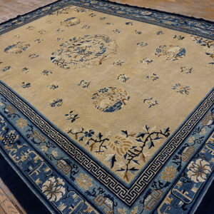 Beige rug featuring blue and camel floral patterns and detailed multiple borders on rustic wood flooring.