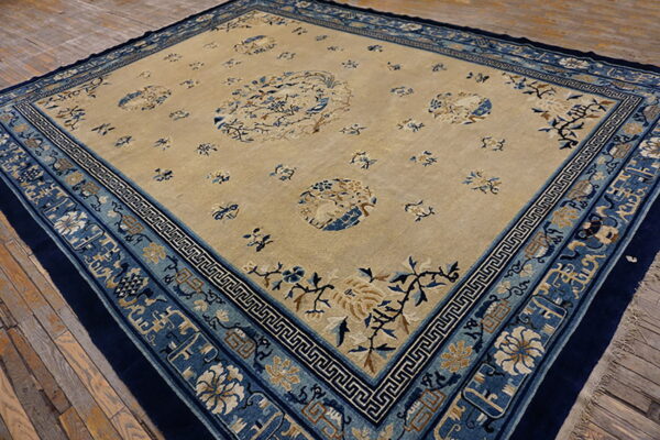 Beige rug featuring blue and camel floral patterns and detailed multiple borders on rustic wood flooring.