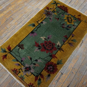 Gold-bordered rug featuring a teal center with red, purple, and yellow floral patterns on distressed wood planks.