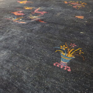 Close up of a plush dark blue rug with colorful stylized deer and flower basket designs.