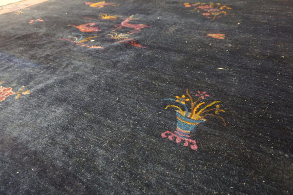 Close up of a plush dark blue rug with colorful stylized deer and flower basket designs.