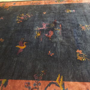 Low pile navy rug with scattered colorful patterns of dragons, birds, and flowers, framed by a rust-colored border.