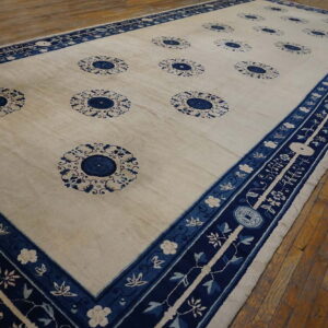 Off-white rug with repeating blue rosette medallions and wide, highly decorative navy blue floral borders.