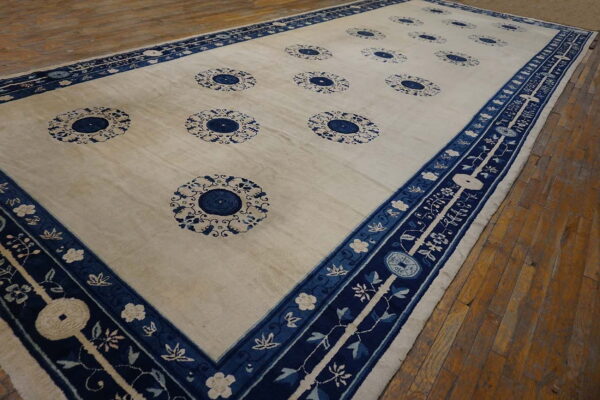 Off-white rug with repeating blue rosette medallions and wide, highly decorative navy blue floral borders.