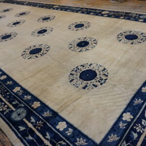Cream area rug featuring twelve deep blue medallion patterns and a complex floral border on wood flooring.