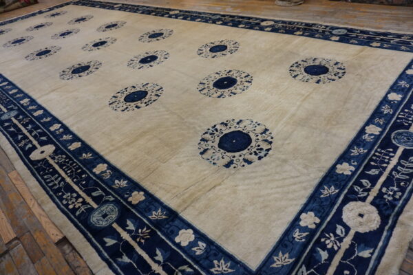 Cream area rug featuring twelve deep blue medallion patterns and a complex floral border on wood flooring.