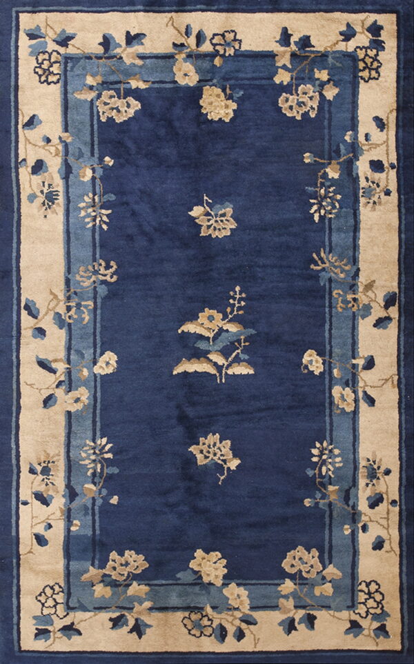 Navy blue rug with beige and pale blue floral sprays and a wide, layered tan outer border.
