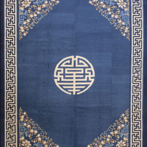 Deep blue rug with a beige geometric medallion, floral corners, and a white and dark blue key border.