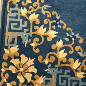 Deep blue rug texture with intricate tan floral scroll and light blue geometric corner designs.