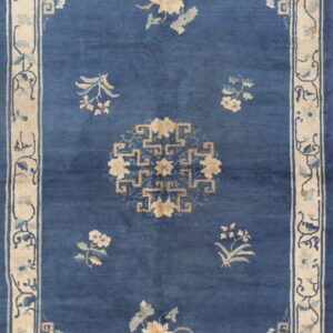 Deep blue rug with scattered tan floral motifs, a central medallion, and a wide cream and blue border.
