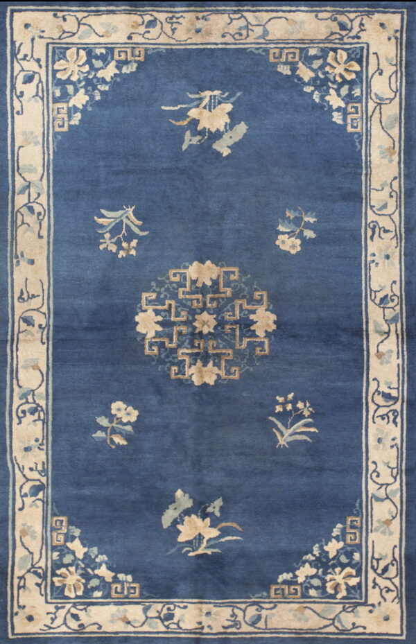 Deep blue rug with scattered tan floral motifs, a central medallion, and a wide cream and blue border.