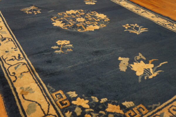 Deep blue rug featuring tan and light blue floral patterns and geometric motifs on a wood floor.
