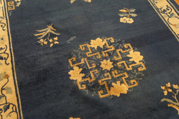 Low-pile navy rug with tan and pale blue floral sprays and a central geometric medallion design.