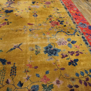 A bright gold rug with detailed blue, pink, and purple floral patterns and a wide red floral border.