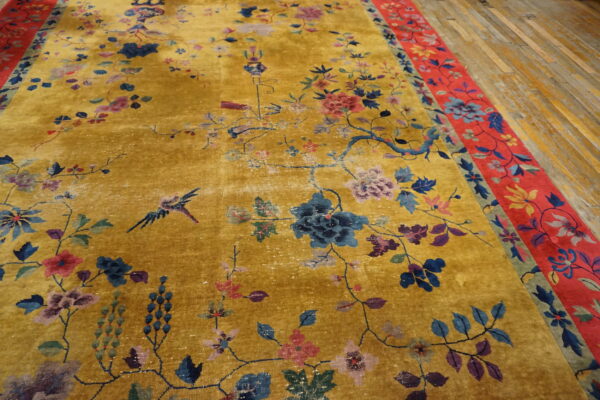 A bright gold rug with detailed blue, pink, and purple floral patterns and a wide red floral border.