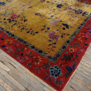 Shimmering golden yellow rug with a colorful floral pattern and a wide red border on wood floors.