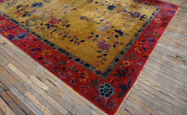 Shimmering golden yellow rug with a colorful floral pattern and a wide red border on wood floors.