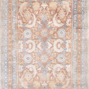 A traditional area rug featuring a faded pattern in rusty pink, cream, and soft blue tones.