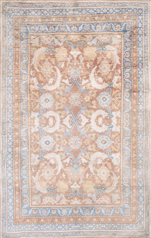 A traditional area rug featuring a faded pattern in rusty pink, cream, and soft blue tones.