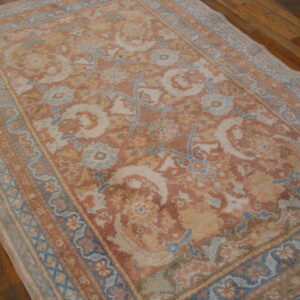 Textured rug featuring ornate patterns in muted terracotta, pale blue, and cream on a plank wood floor.