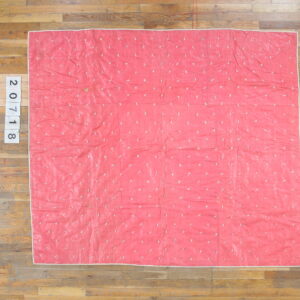Bright pink textile with scattered white irregular shapes and a light border on wood plank flooring.