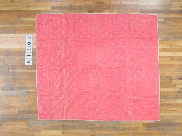 Bright pink textile with scattered white irregular shapes and a light border on wood plank flooring.