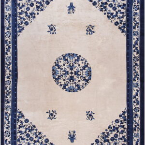 Rectangular cream rug featuring a central blue medallion and intricate navy floral patterns in the corners and border.